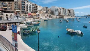 A marina with boats docked, a waterfront promenade, and buildings in the background. - Cozy 1BR home in the centre of St Julians w/WIFI (San Ġiljan)