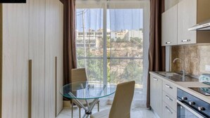 A small kitchen with a glass table and chairs, a sink, and cabinets. - Cozy 1BR home in the centre of St Julians w/WIFI (San Ġiljan)