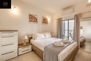 Een hotelkamer met een bed, nachtkastjes, een kledingkast en een balkon met uitzicht.