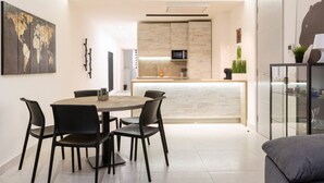 A modern kitchen with a central island, a dining area with a round table and chairs, and a seating area with a sofa.