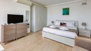 A modern hotel room with a bed, a TV, a wardrobe, and a desk.