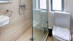 A modern bathroom with a glass-enclosed shower, a toilet, and a sink.