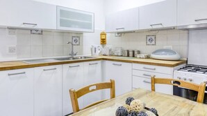 A modern kitchen with white cabinets, a wooden countertop, a stove, and a dining table with chairs. - Peaceful 1BR maisonette with Sofa Bed with WIFI ! (San Pawl il-Baħar)
