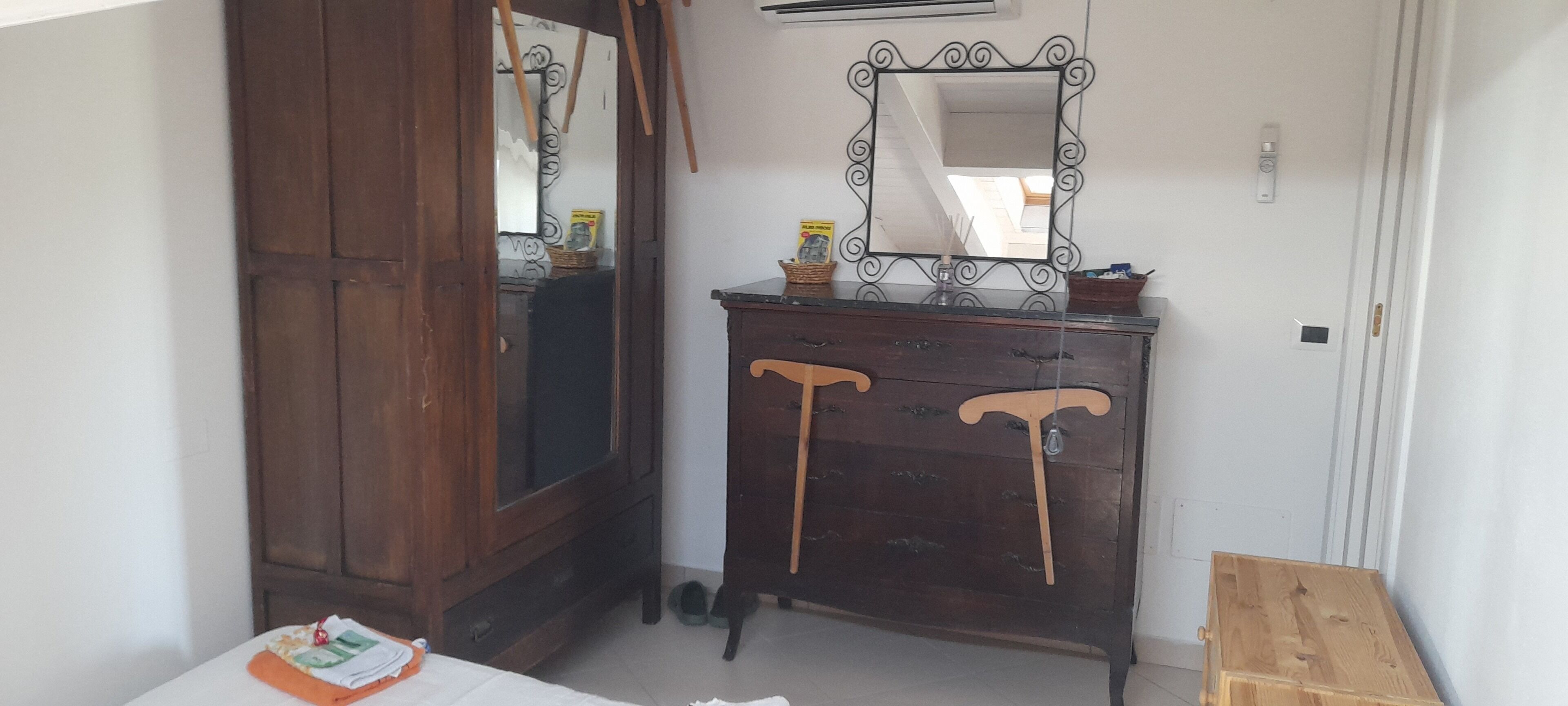 A room with a wooden wardrobe, a mirror, and a small wooden table.