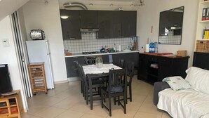 Un espace de vie compact comprenant un coin repas, une kitchenette et un canapé.