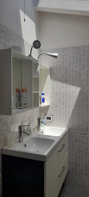 Een moderne badkamer met een grote spiegel, een witte wastafel en een inbouwkast.