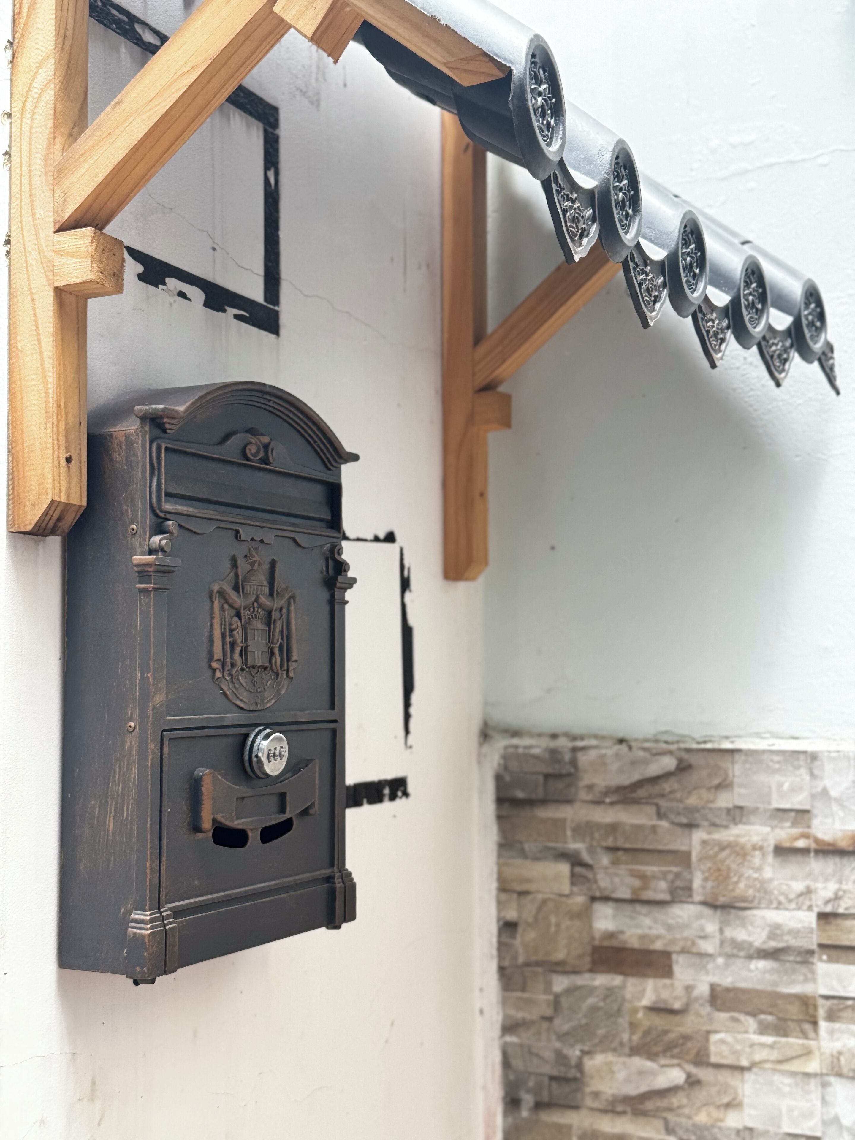 Una caja fuerte de estilo vintage montada en una pared, con un muro de piedra al fondo.