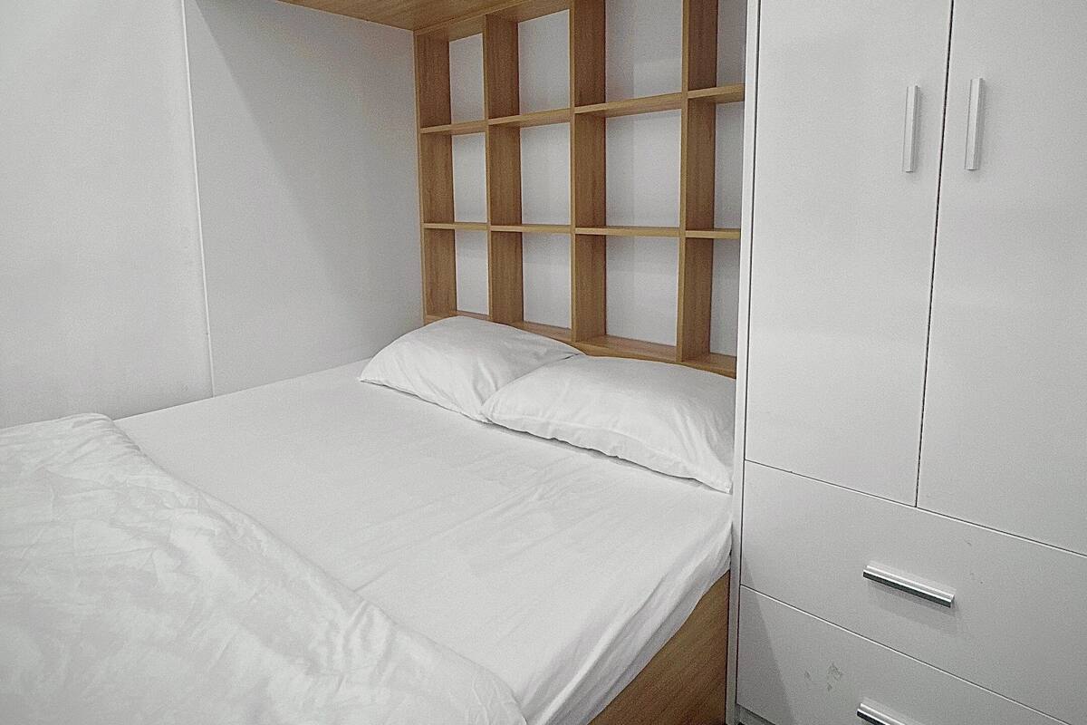 A bedroom with a bunk bed, a wardrobe, and a window.