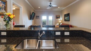 A kitchen with a granite countertop, stainless steel sink, and a ceiling fan.