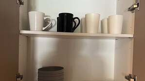Un armario de cocina con estantes que contienen diverso menaje, un tostador y un enchufe.