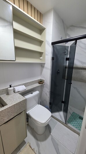 A modern bathroom with a toilet, sink, and shower area. - Mirante do Porto Vista Mar 304 byLP (Ipojuca)