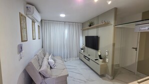 A modern living room with a sofa, TV, and built-in entertainment unit. - Mirante do Porto Vista Mar 304 byLP (Ipojuca)