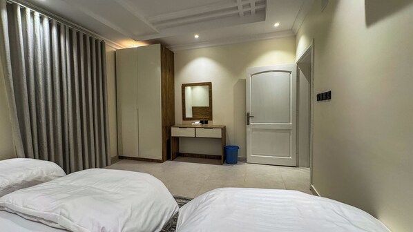 A hotel room with a bed, a bedside table, a mirror, a wardrobe, and a trash bin.