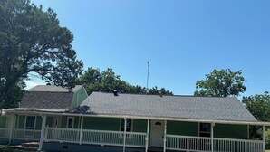 A single-story house with a green exterior and white porch railings. - Entire Home  4-bedroom house in LakeWhitney Estates with WiFi, AC. Book now! (Whitney)