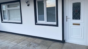 A white building with black trim around windows and a door, featuring a patterned window and a door with a glass panel. - Stunning Truro 1-bed - Sleeps 2 & Parking (Truro)