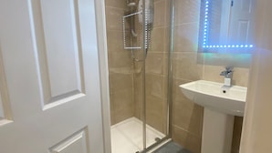 A bathroom with a glass shower enclosure, a sink, and a mirror with LED lights. - Stunning Truro 1-bed - Sleeps 2 & Parking (Truro)