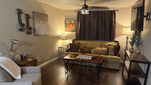 Un salon avec un canapé, une table basse, une lampe et un téléviseur.