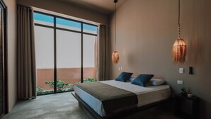 A bedroom with a large bed, a view through a window, and a hanging light fixture. - Casa Ita - Private Villas (Palomino)