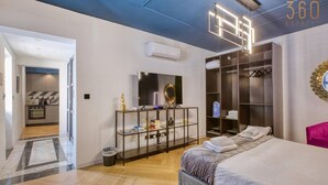 A modern bedroom with a large bed, a walk-in closet, and a kitchenette.