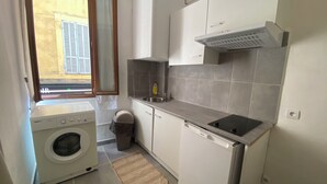 A compact kitchen with a washing machine, a sink, and a stove.