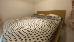 A single bed with a polka dot bedspread, a wooden headboard, and a small bedside table with a lamp.