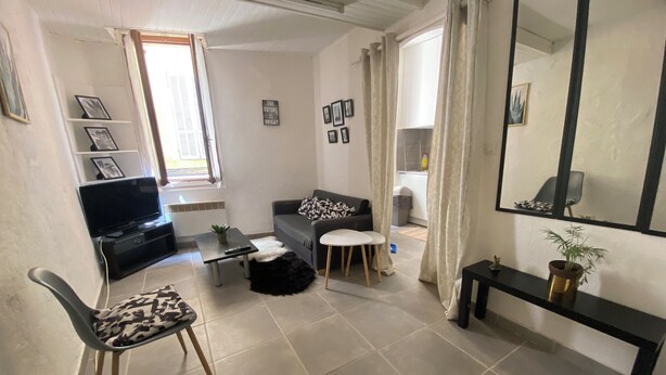 A living room with a sofa, a coffee table, a TV, a chair, and a small table with a plant.