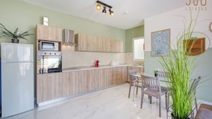 Una cocina moderna con armarios de madera, un refrigerador blanco, un horno empotrado y un comedor con una mesa y sillas.