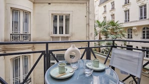 A balcony with a table set for two, a vase, and a chair. - Stunning AC Duplex Apartment - Champs Elysees (Paris)