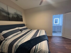 Un dormitorio con una cama grande, un ventilador de techo y vistas al baño.