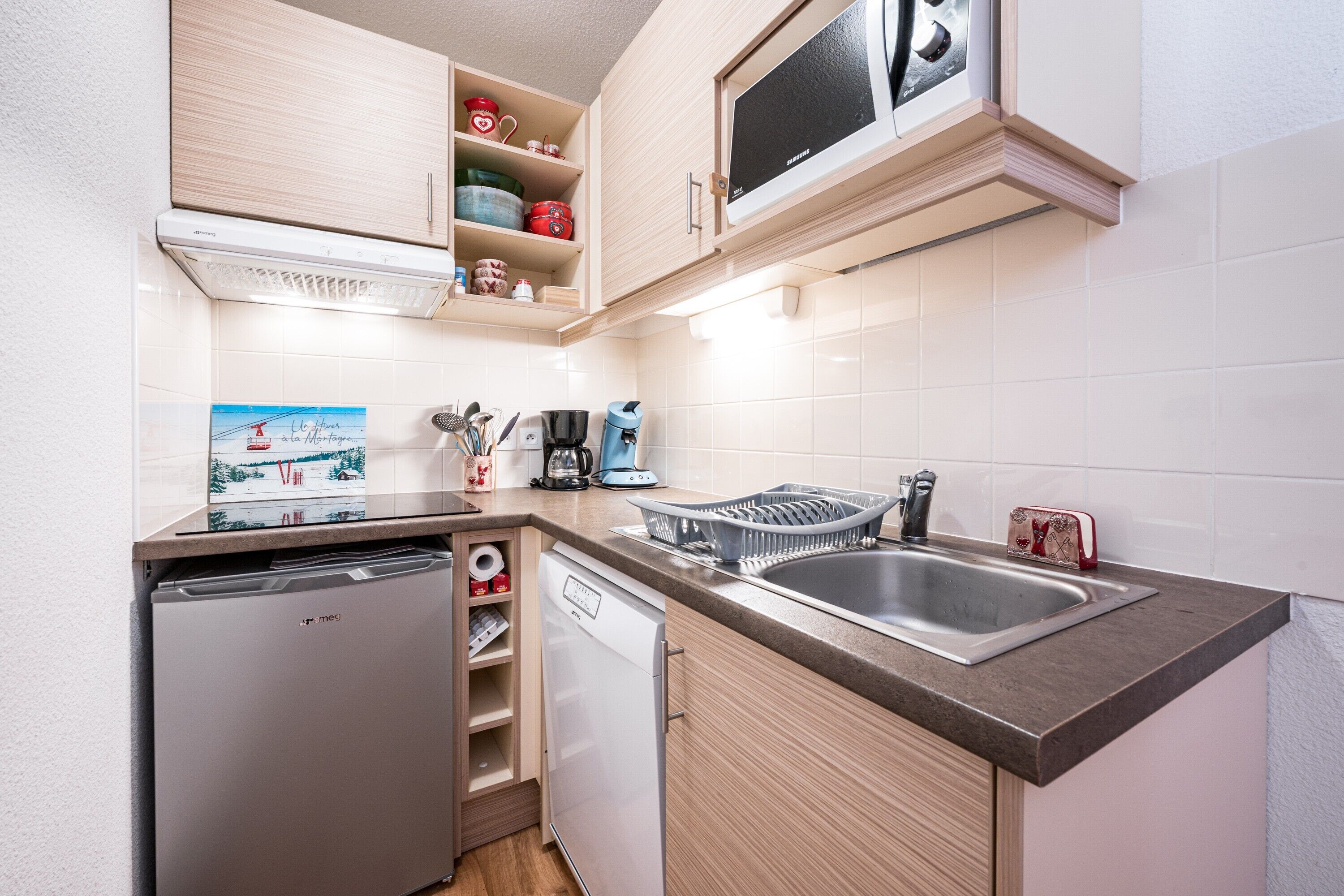 Una cocina compacta equipada con lavavajillas, cafetera y microondas.