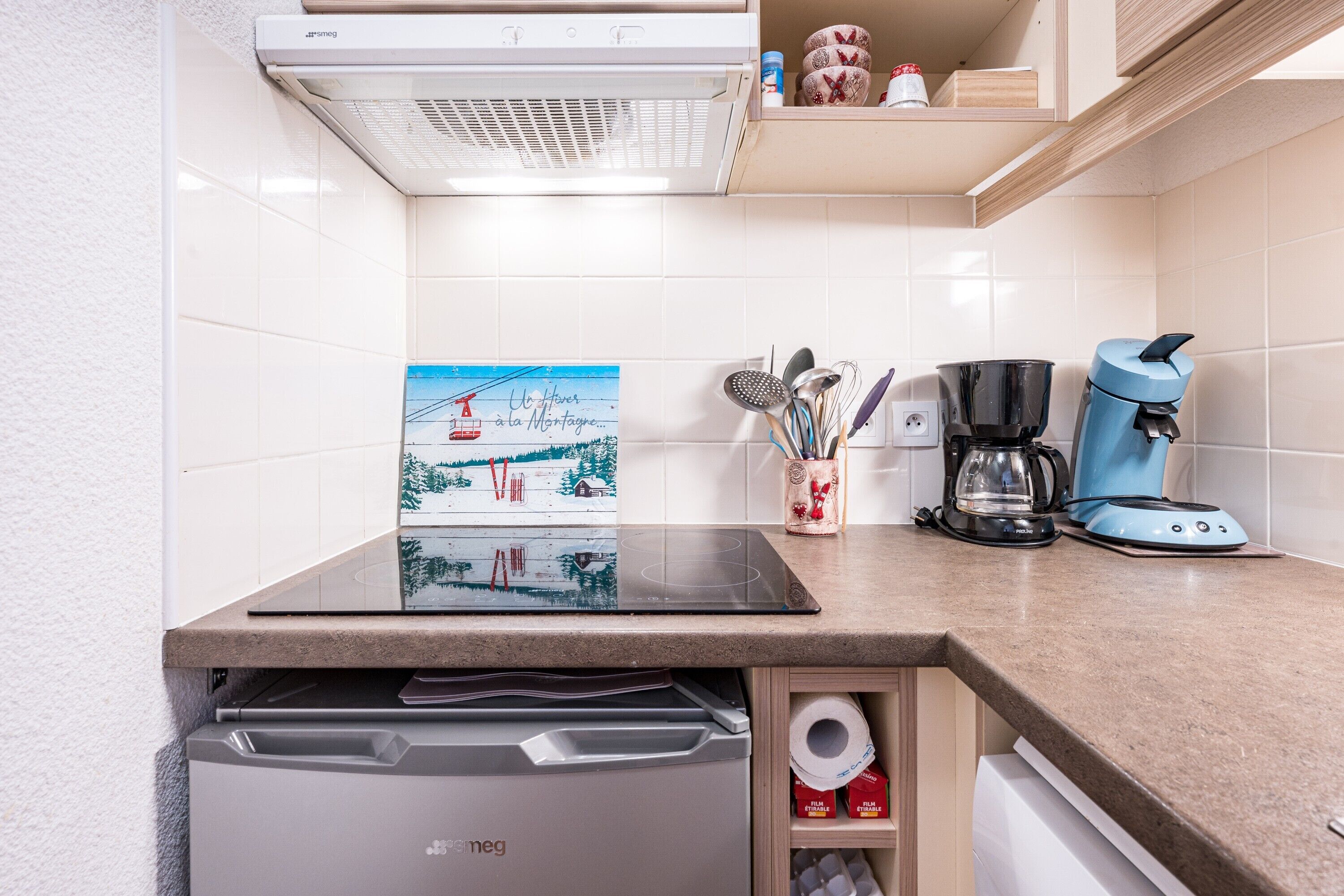 Een keuken met een vaatwasser, een koffiezetapparaat en een schilderij aan de muur.