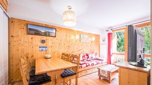 A wooden interior with a dining table, chairs, a sofa, and a television. - Quiet Apartment at the Foot of the Slopes (Valmeinier)