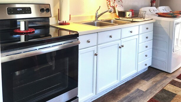 A kitchen with white cabinets, stainless steel appliances, a double sink, and a patterned rug. - SPOTLESS Geneva home!  MINUTES to Wineries, Spires, Downtown, & the Strip! (Geneva)