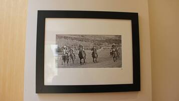 A framed black and white photograph of jockeys on horses in a race.