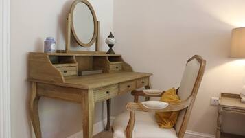 Une coiffeuse en bois, avec un miroir, une lampe et une chaise dotée de coussins.