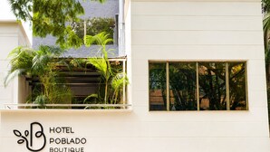 A modern hotel with a white facade, a visible entrance, and a balcony with plants. - Hotel Poblado Boutique (Medellín)