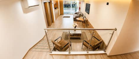 A modern hotel lobby with a glass railing, seating area, and a view of the street outside.