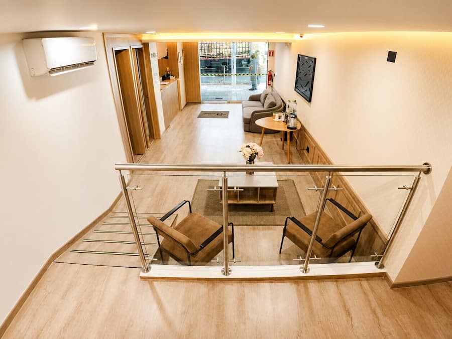 A modern hotel lobby with a glass railing, seating area, and a view of the street outside.