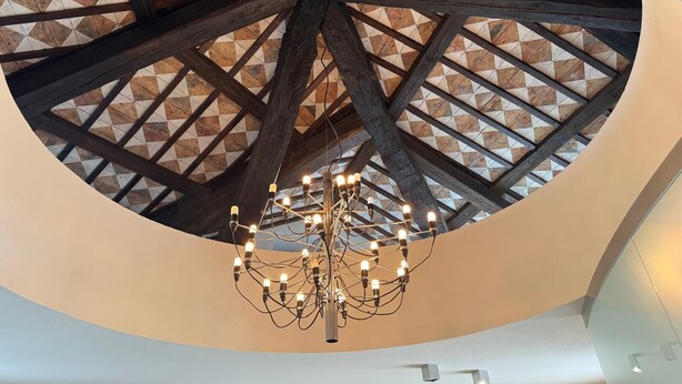 Techo circular con un diseño geométrico de baldosas y vigas de madera a la vista.