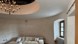 Un salón espacioso con un conjunto de sofás moderno, una araña y un jarrón decorativo con flores.