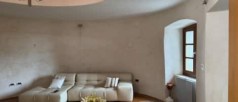 Ein großzügiges Wohnzimmer mit einer modernen Sofagarnitur, einer Kristallleuchtre und einer dekorativen Vase mit Blumen.