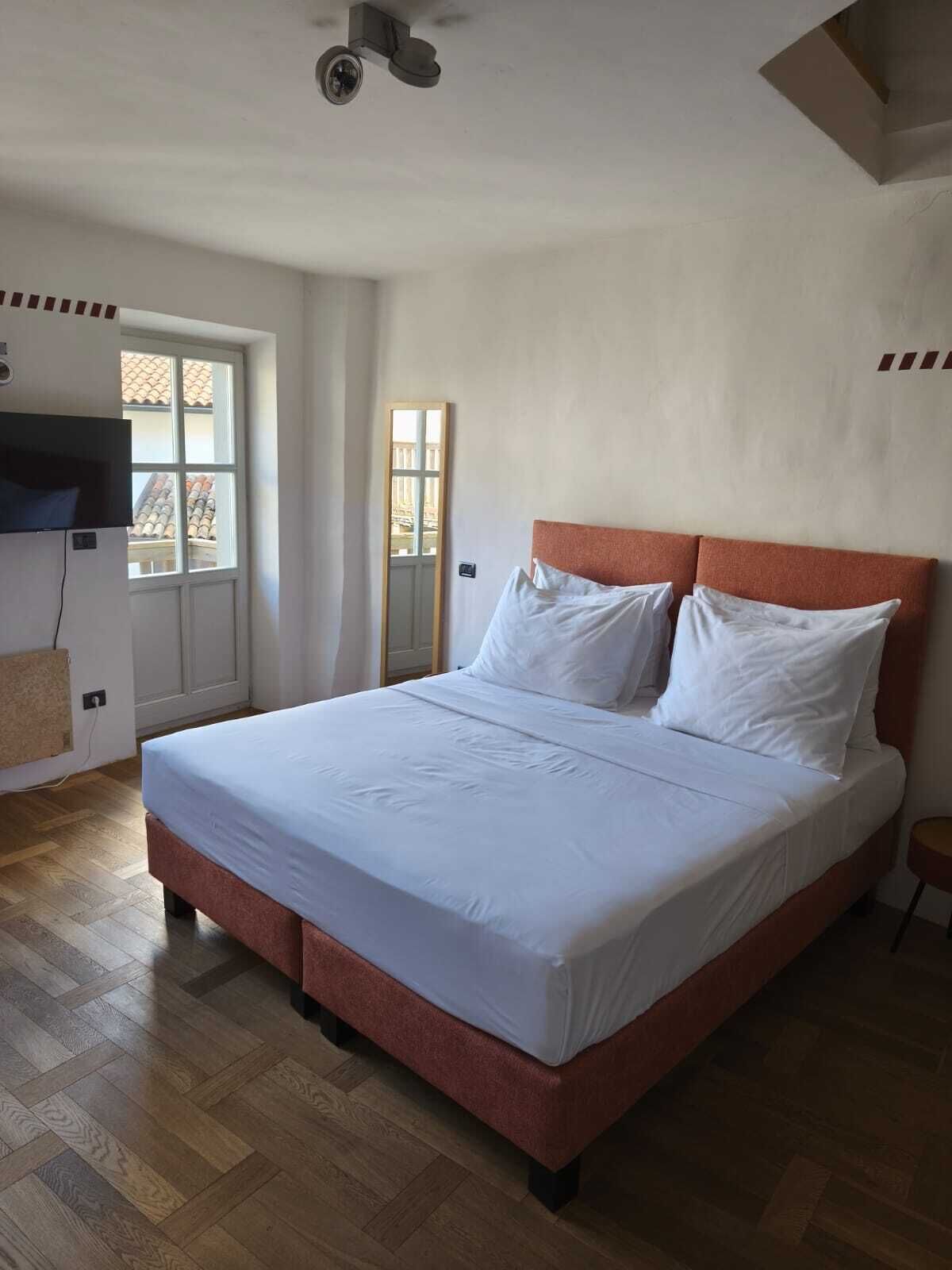 Ein Schlafzimmer mit einem großen Bett, einem Deckenventilator, einem Fenster und einer Tür.