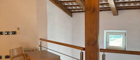 A bedroom with a wooden ceiling, a bed, a desk, and a chair.