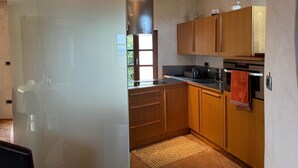 Una cocina moderna con armarios de madera, una campana extractora de acero inoxidable y un ventanal que proporciona luz natural.