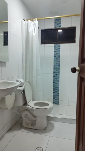 A bathroom with a toilet, sink, and shower curtain. - Hotel Dorado Baq (Barranquilla)