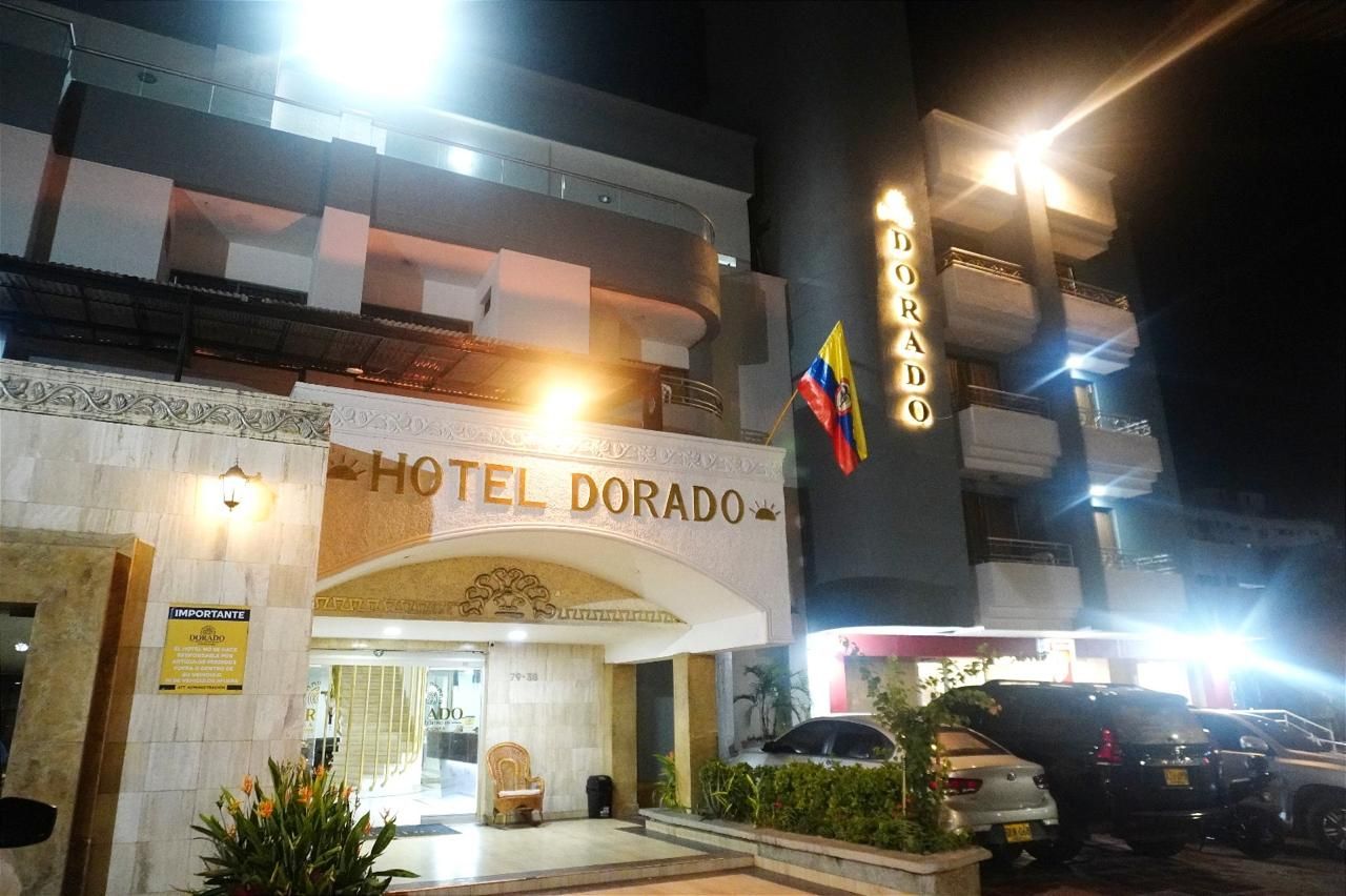 Exterior del Hotel Dorado, con una entrada destacada, una bandera y señalización iluminada.