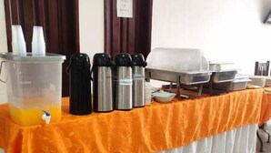 A buffet table with a drink dispenser, thermos flasks, and food containers. - Hotel Dorado Baq (Barranquilla)