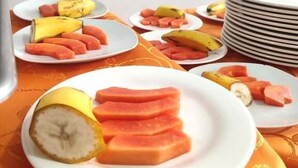 A table with plates of sliced fruits and a stack of plates. - Hotel Dorado Baq (Barranquilla)