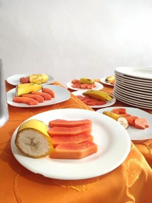 A table with plates of sliced fruits and a stack of plates. - Hotel Dorado Baq (Barranquilla)