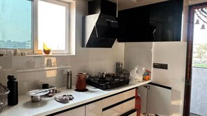 A modern kitchen with a gas stove, stainless steel appliances, and a window with a city view. - Independent floor for rent in Hyderabad (Hayathnagar_Khalsa)